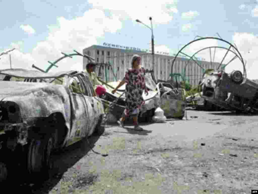 Жители Андижана проходят мимо сожженных автомобилей после столкновений, когда войска стреляли в демонстрантов.