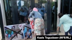 Активисты организации «Обеспечьте народ жильем» складывают антиплакат «Шал, кет!» у входа в консульство США. Алматы, 31 мая 2016 года.