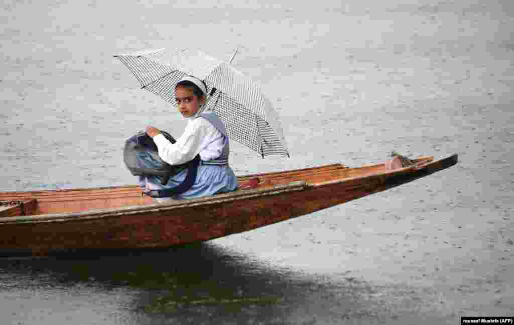 A Kashmiri schoolgirl sits on a boat on Dal Lake during a rainfall in Srinagar. (AFP/Tauseef Mustafa)