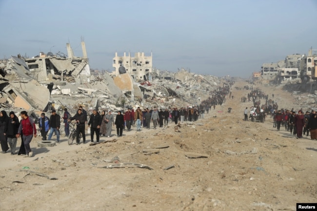 Palestinezët e zhvendosur kalojnë rrënojat në përpjekje për t'u kthyer në shtëpitë e tyre në veri të Rripit të Gazës më 19 janar.