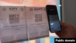 Сканирование QR-кода на смартфон с приложением Ashyq, разделяющим казахстанцев «по цветам» для пропуска в различные общественные места.