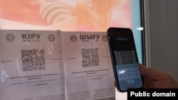 Сканирование QR-кода на смартфон с приложением Ashyq, разделяющим казахстанцев «по цветам» для пропуска в различные общественные места.
