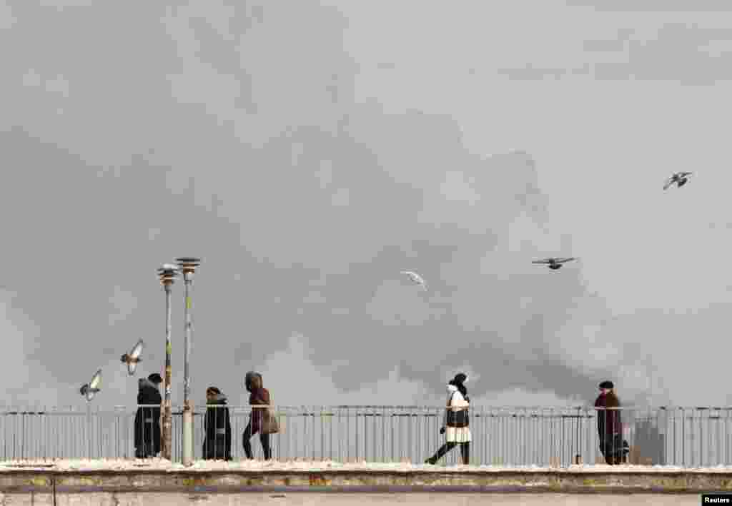 People walk over a bridge in front of the chimneys of a city power plant in subzero conditions in Kyiv. 