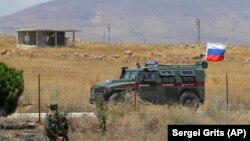 Војник на сириската армија стои до руско воено  возило во близина на градот Алхураја, 14.08.2018. 