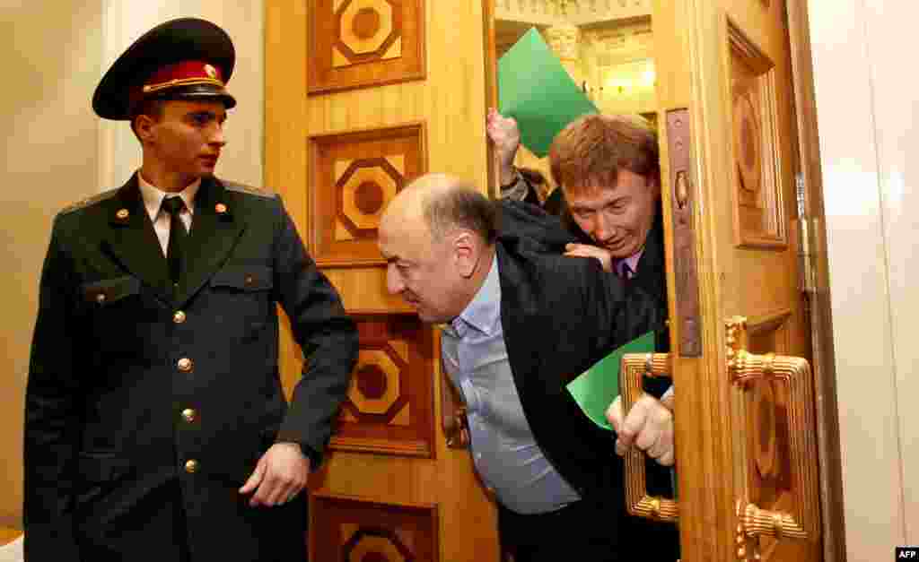A policeman steps aside as father and son Andriy and Oleksandr Tabalov are driven out of Kyiv's parliament chamber under a hail of fists and insults. The pair were accused of preparing to switch sides and join the ruling party in December 2012. 
