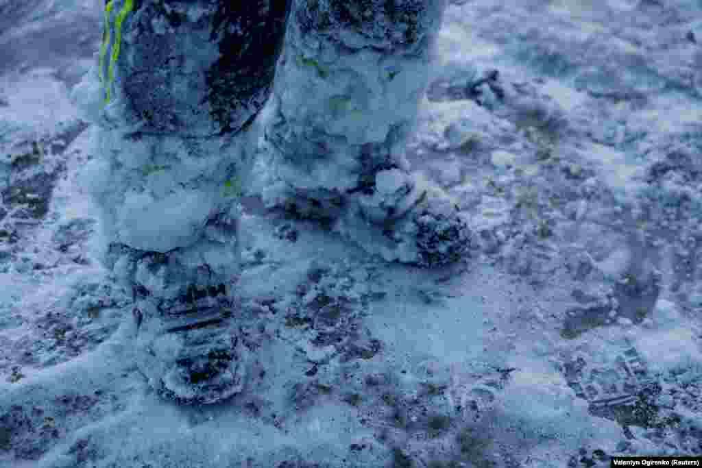 Перед цим мокрі, а тепер замерзлі ноги пожежника, який майже цілу ніч гасив пожежу після нічних ударів російських безпілотників та ракет по Києву. Київ, 24 січня 2026 року