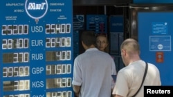 Люди рядом с пунктом обмена валют в день, когда власти объявили о переходе к политике «свободно плавающего обменного курса». Алматы, 20 августа 2015 года.