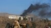 Afghan security forces keep watch as smoke rises from the Intercontinental Hotel in Kabul on January 21.