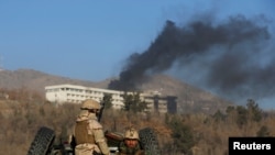 Afghan security forces keep watch as smoke rises from the Intercontinental Hotel in Kabul on January 21.