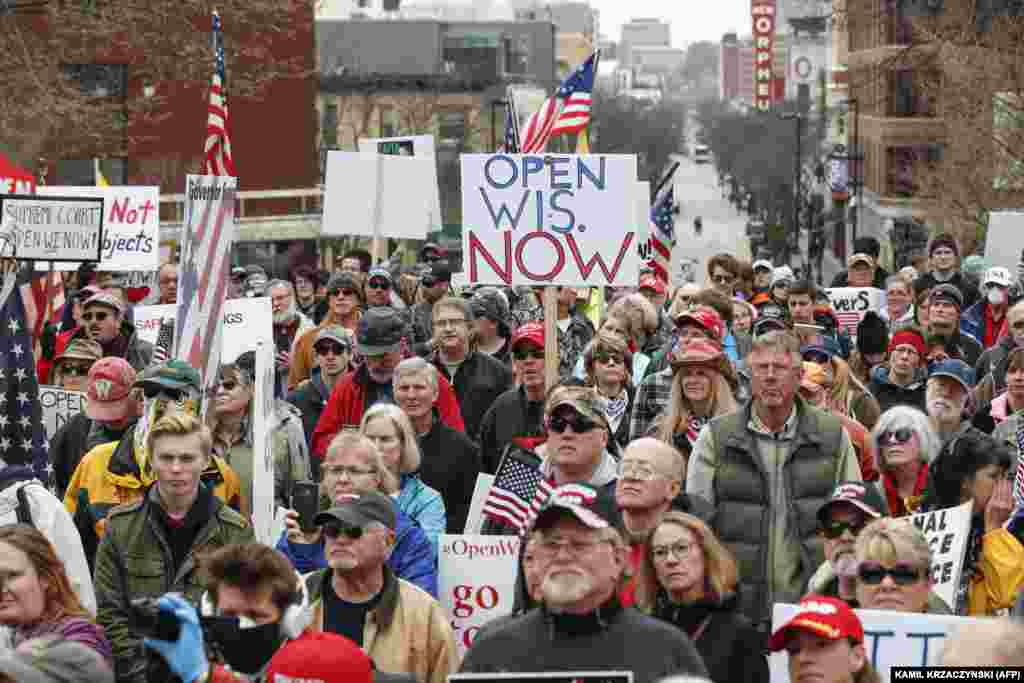 People hold signs during a protest against the coronavirus shutdown in front of State Capitol in Madison, Wisconsin, on April 24, 2020.