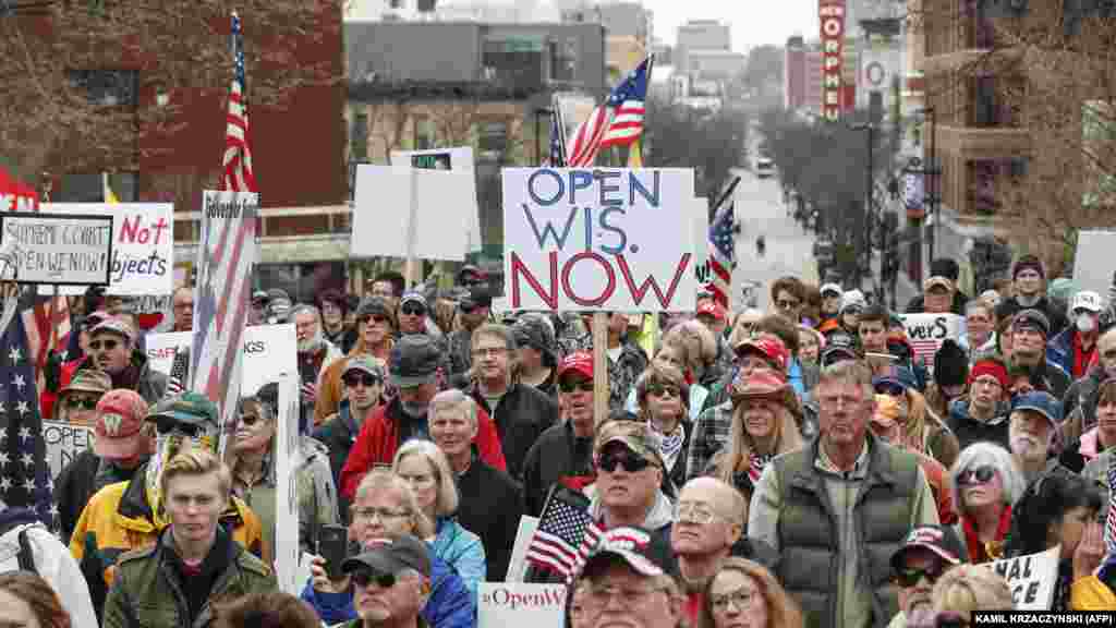 People hold signs  during a protest against the coronavirus shutdown in front of State Capitol in Madison, Wisconsin, on April 24, 2020.