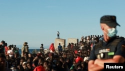 Migranti čekaju u redu za hranu i piće od Crvenog krsta, nakon masovnog prelaska migranata iz Maroka na špansku teritoriju, u Ceuti, Španija, 3. avgusta 2026. 