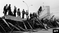 People stand on a barricade in front of the Russian White House in Moscow, August 21, 1991.