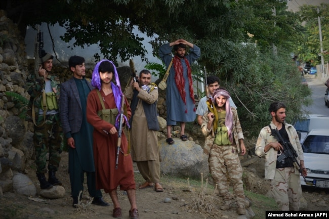 Armed men who have recently joined the fight against the Taliban stand along a road in Bazarak, Panjshir Province, on August 18.