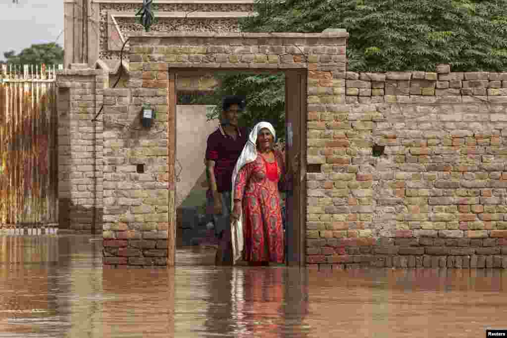 Flood victims wait to be evacuated by boat from their flooded house following heavy rain in Jhang, Punjab Province.