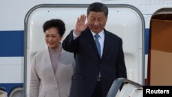Chinese President Xi Jinping waves next to his wife, Peng Liyuan, as they board their plane for Hungary following a two-day state visit to Serbia. 