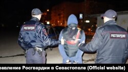 Сотрудники Росгвардии ведут задержанного жителя Самары в Севастополе