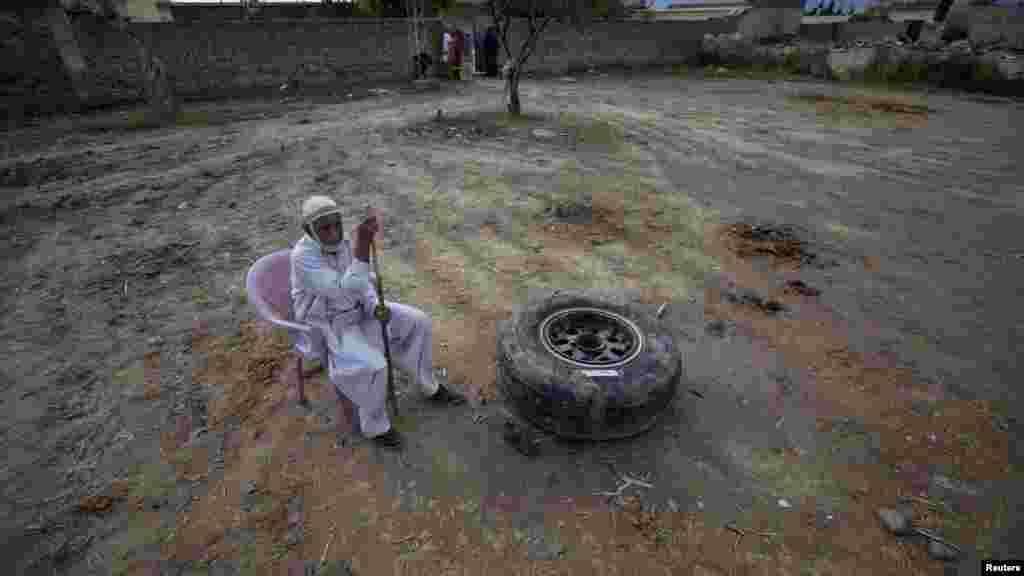 An elderly Islamabad resident sits next to a tire from the ill-fated Boeing 737. (Reuters/Faisal Mahmood)