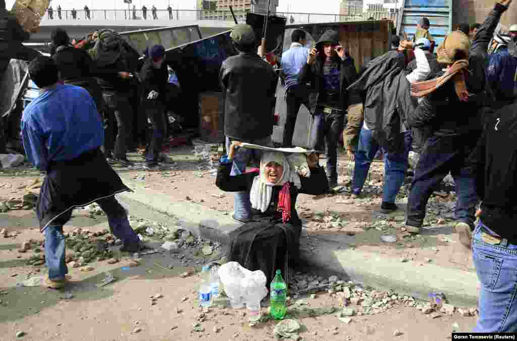 An opposition supporter protects herself from stones raining down during mass protests near Tahrir Square in Cairo in February 2011. The Egyptian protests were part of what would come to be called the &quot;Arab Spring.&quot;
