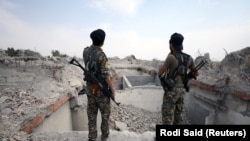 Syrian rebel fighters stand near the destroyed Uwais al-Qarni shrine in Raqqa, Syria, on September 16.