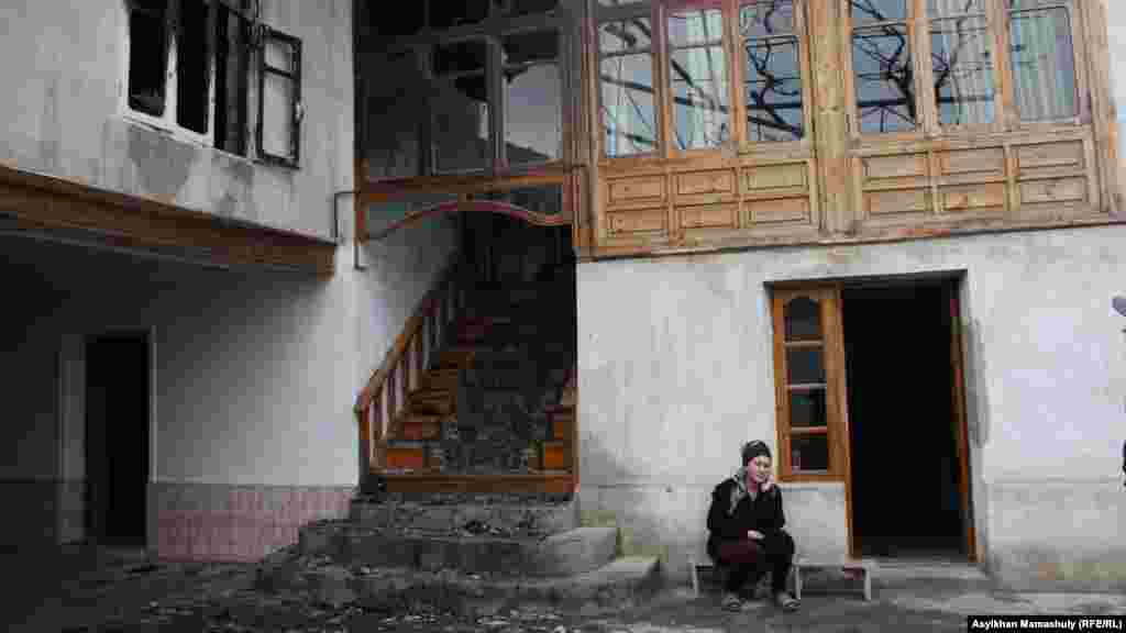 Жена Адильжана Хасанова сидит у подожженного дома.