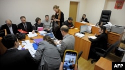 The plaintiffs (rear) and the respondents (front) in a suit against Madonna sit at a table in a courtroom in St. Petersburg on November 22.