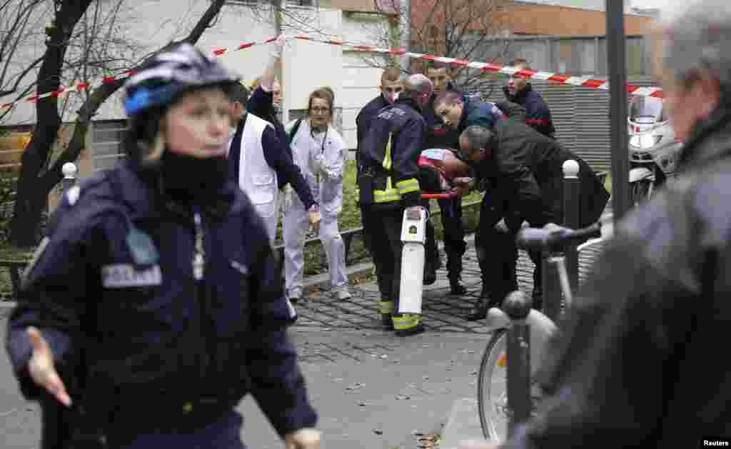 Пожежники виносять поранену жертву нападу перед будівлею Charlie Hebdo