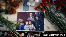 A photo of a young family is surrounded by candles, flowers, and toys during a ceremony commemorating the victims of a fire in a shopping mall in the Siberian city of Kemerovo, in the center of Moscow on March 27.