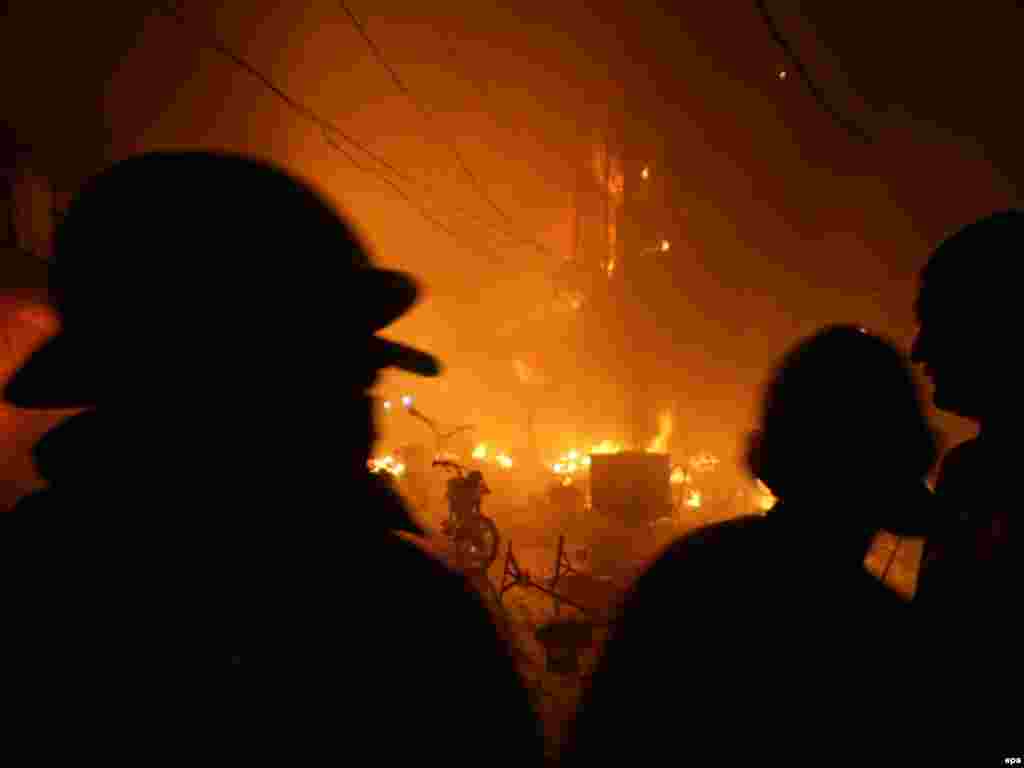 Firefighters try to extinguish a blaze after an explosion in Lahore, Pakistan. - As many as 48 people were killed in two bombings in eastern Pakistan on December 7 at a market crowded with women and children. Photo by Rahat Dar for epa