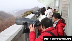 La granița cu Coreea de Nord, turiștii se uită de partea cealaltă a frontierei, din clădirea Unification Observation Post din Paju
