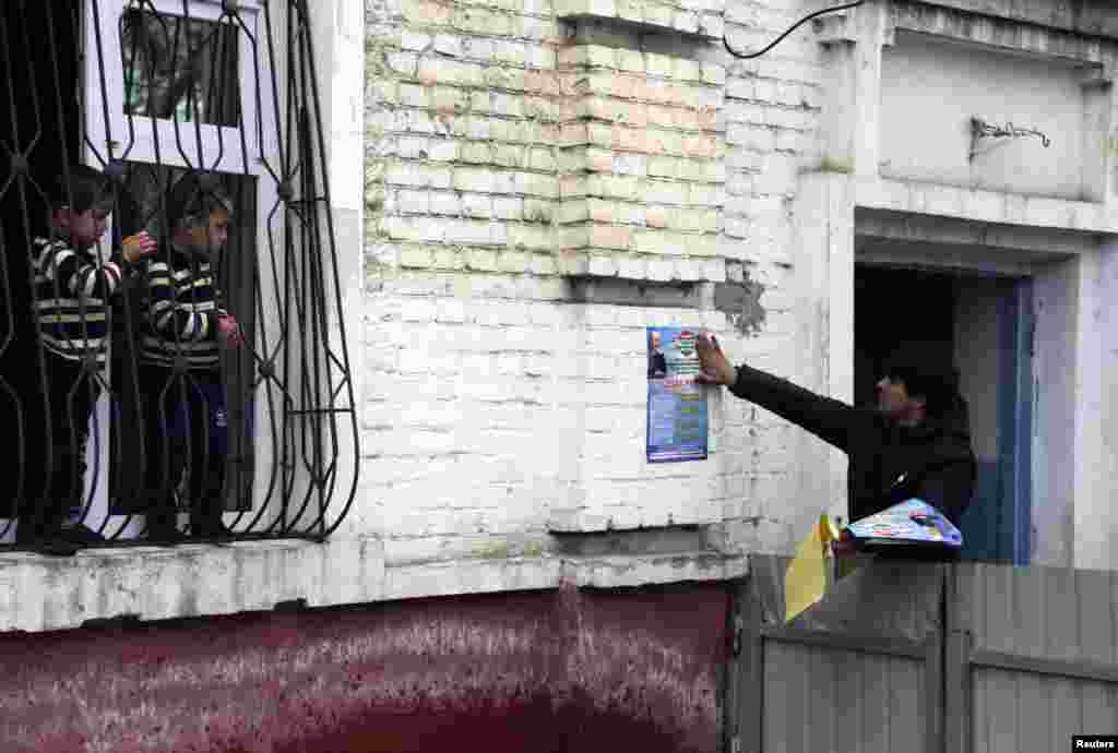 Children watch a supporter of the Islamic Renaissance Party of Tajikistan (IRPT) paste a campaign poster on a wall in the capital, Dushanbe. (Reuters/Nozim Kalandrov)