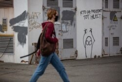 Дівчина проходить повз трансформаторну будку з графіті «Хто не працює, той не їсть»