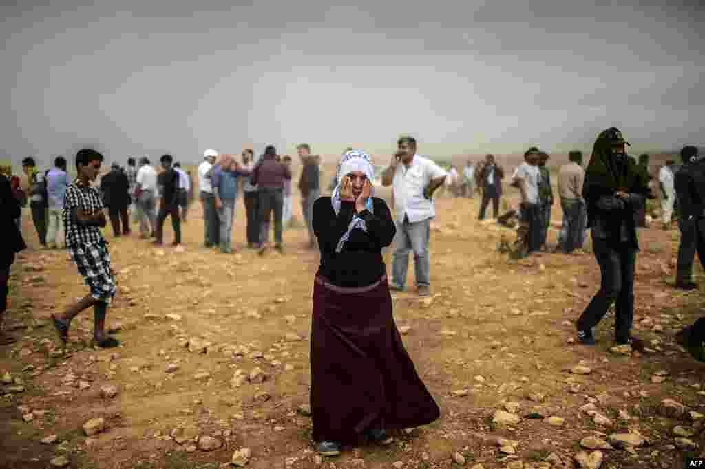 A Syrian Kurdish woman wipes her eyes during a dust storm on a hill where she and others stand watching clashes between jihadists of the Islamic State and Kurdish fighters&nbsp;in Sanliurfa Province in southeastern Turkey. Tens of thousands of Syrian Kurds flooded into Turkey, fleeing an onslaught by Islamic State militants. (AFP/Bulent Kilic) 