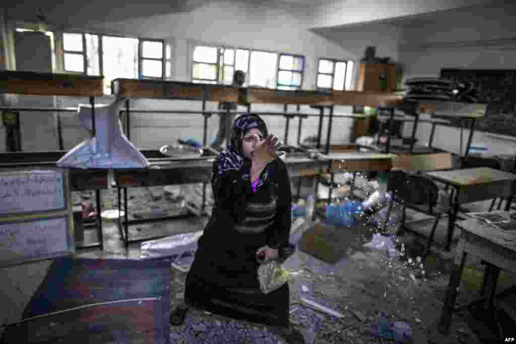 A desperate Palestinian woman throws debris in the air in a classroom where she is taking shelter with her family following Israeli army shelling in the area. (AFP/Marco Longari)