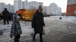 Жителка на Киев носи кутии с топла храна, приготвена от неправителствената организация "Световна централна кухня", 17 януари 2026 г.