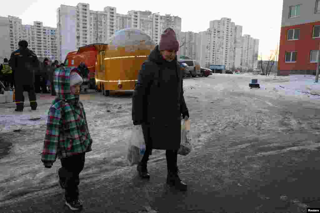 O femeie, ducând cutii cu supă pregătită de organizația de caritate World Central Kitchen și oferită locuitorilor Kievului pentru a se încălzi, pe 17 ianuarie.