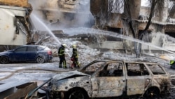 Пожарные работают на месте здания, в которое попал российский беспилотник во время атаки России на Украину, Киев, Украина, 12 января 2026 года