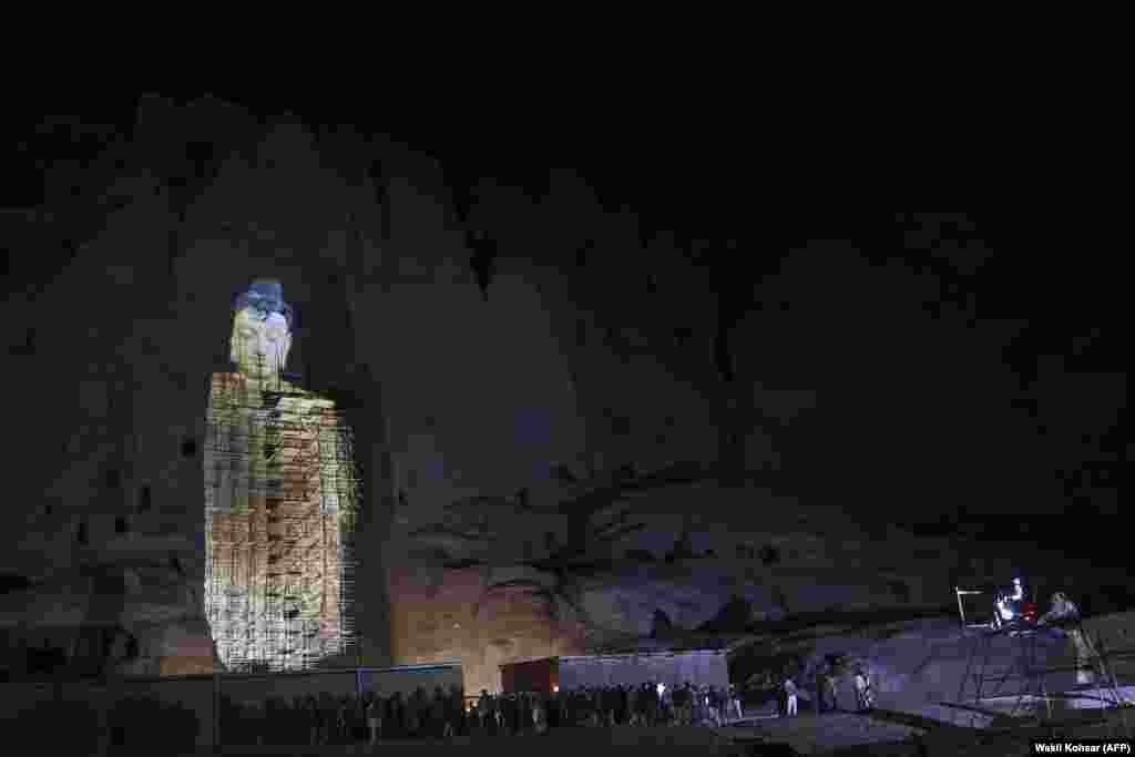 People watch a three-dimensional projection of the 56 meter-high Salsal Buddha at the site where the Buddhas of Bamiyan statues stood before being destroyed by the Taliban in March 2001, in Afghanistan&#39;s Bamiyan Province on March 9. (AFP/Wakil kKohsar)