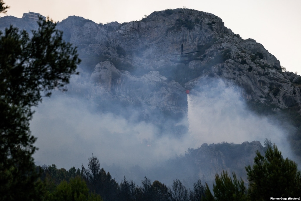 Një helikopter duke hedhur ujë mbi vatrat e zjarrit më 9 gusht. Zona që u përfshi nga flakët është një terren i thepisur, që vështirëson punën e zjarrfikësve.