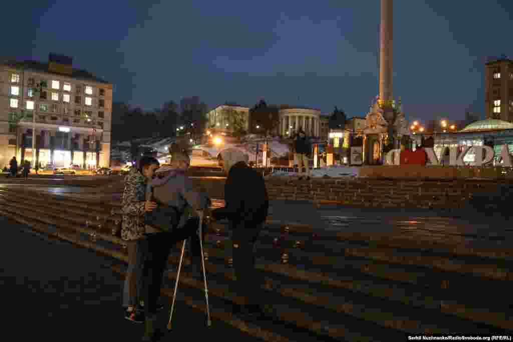 Друзі допомагають пораненому ветеранові запалити лампадку, Київ, 24 лютого 2026 року