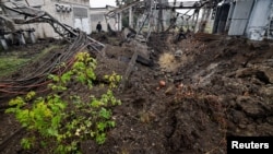 Investigators inspect a crater left by a Russian missile strike on an electrical transformer facility in Kharkiv. 