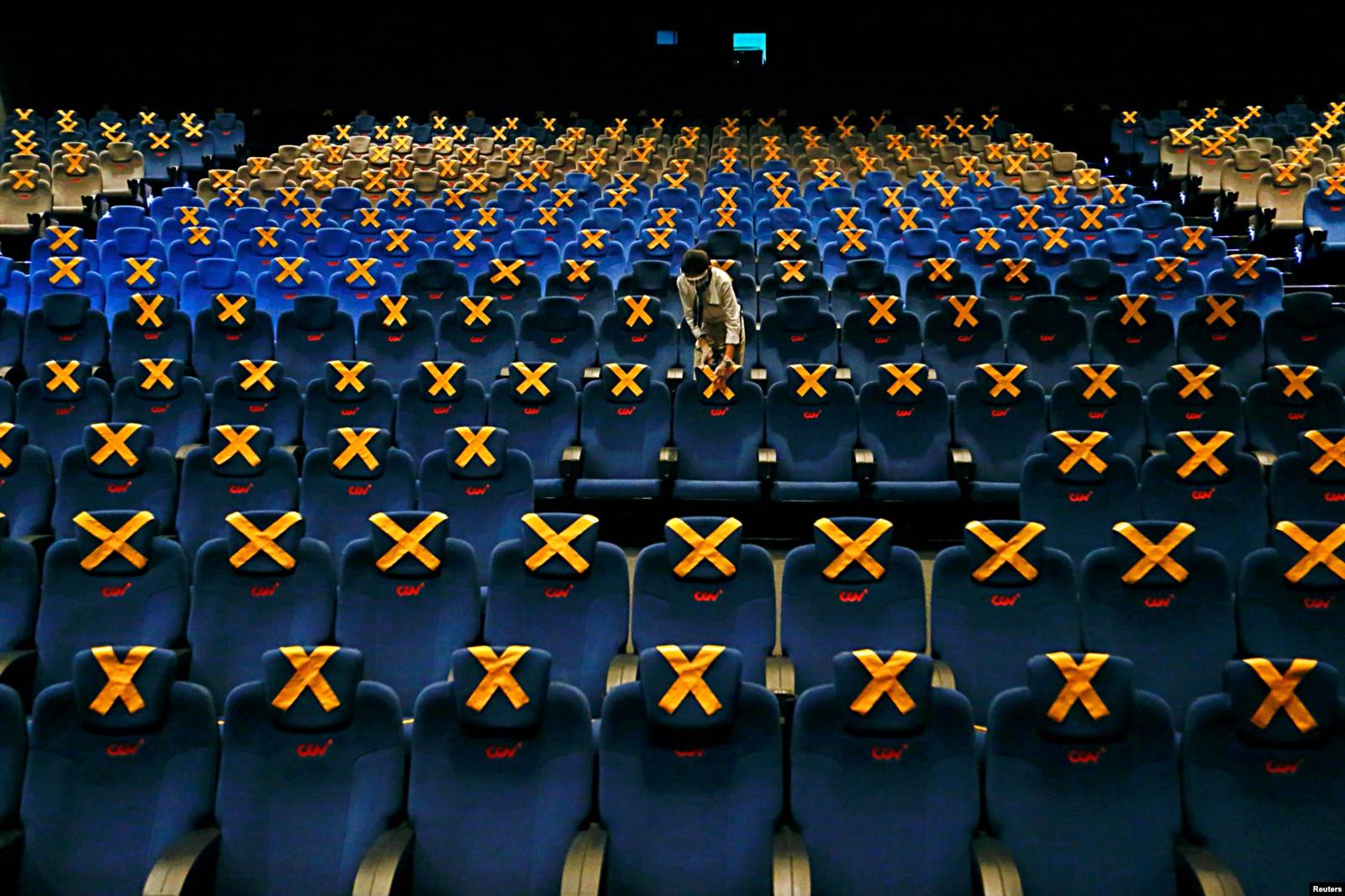 Disa pjesëtarë të stafit duke vënë shenjat për distancë fizike në një sallë kinemaje.