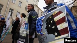 Demonstrators stand outside the Moscow office of the Golos election-monitoring NGO, with one sign branding the group a U.S. agent.