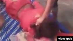 The video shows a man pinning the transgender woman face down on a bed with his foot and beating her bare buttocks with a belt. 