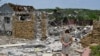 Egy asszony sétál az éjszakai bombázásban lerombolt háznál az ukrajnai Szlovjanszkban 2022. június 1-jén