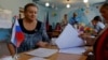 A voter meets with members of an electoral commission at a polling station during local elections held by the Russian-installed authorities in Donetsk, Russian-controlled Ukraine, on September 8.