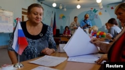 A voter meets with members of an electoral commission at a polling station during local elections held by the Russian-installed authorities in Donetsk, Russian-controlled Ukraine, on September 8.