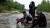 A group of people who tried to cross the Greek-Macedonian border takes a rest after crossing a small river on their way back to a makeshift camp for refugees and migrants at the border near the village of Idomeni, Greece, May 12, 2016. 