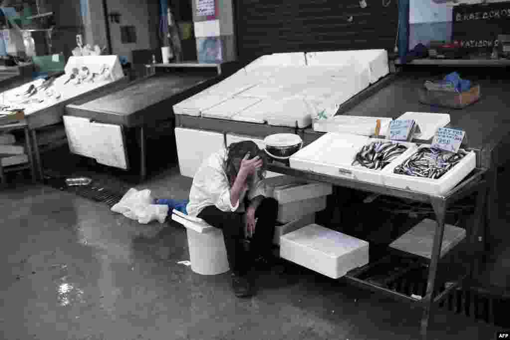 A man working at the central fish market waits for customers in Athens. Greece announced on June 29 that it will shut banks for a week and impose capital controls, pleading for calm after anxious citizens emptied cash machines in a dramatic escalation of the country's debt crisis. (AFP/Angelos Tzortzinis) 