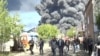 Local officials are pictured in Tuapse, a Black Sea port in southwestern Russia, on April 28 as smoke from a massive blaze rises in the background. Ukraine launched drone strikes on the oil refinery for the third time in two weeks.<br>